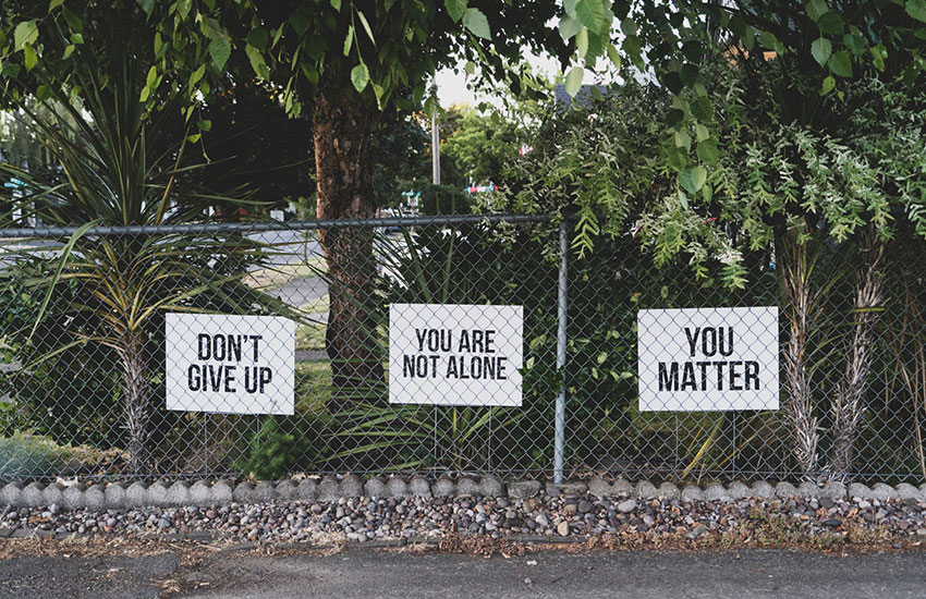 encouraging signs hanging on metal gate