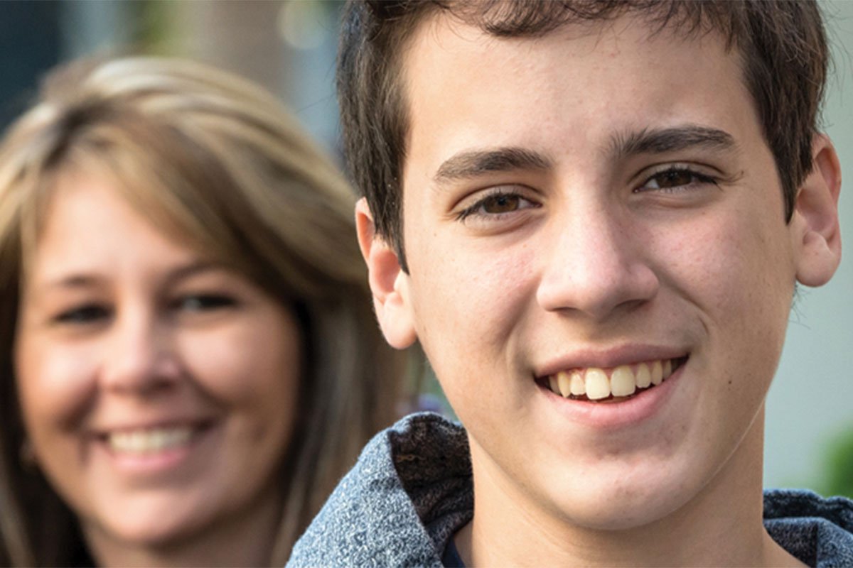 close up of teenage boy with mother in background